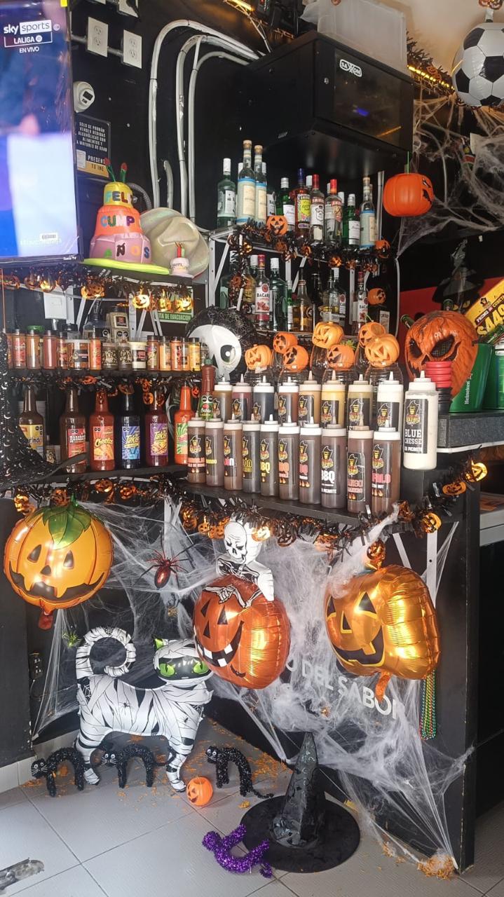 Fotografía de la barra de Gorila Papas Sport con botellas, salsas y decoración de Halloween